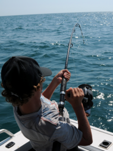 Young man fishing, reeling in a fish.